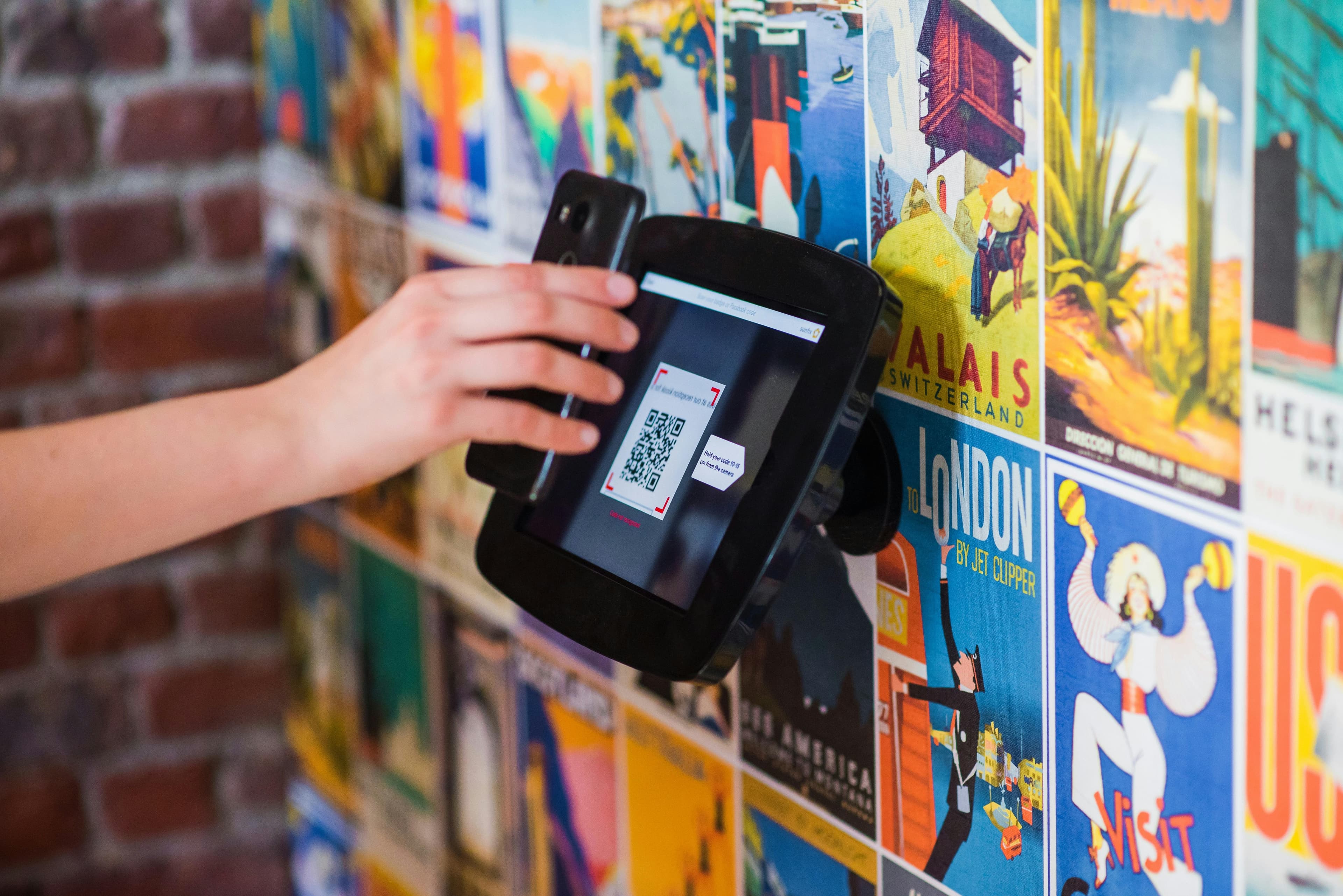 Hand scanning a QR code with a mobile check-in device.