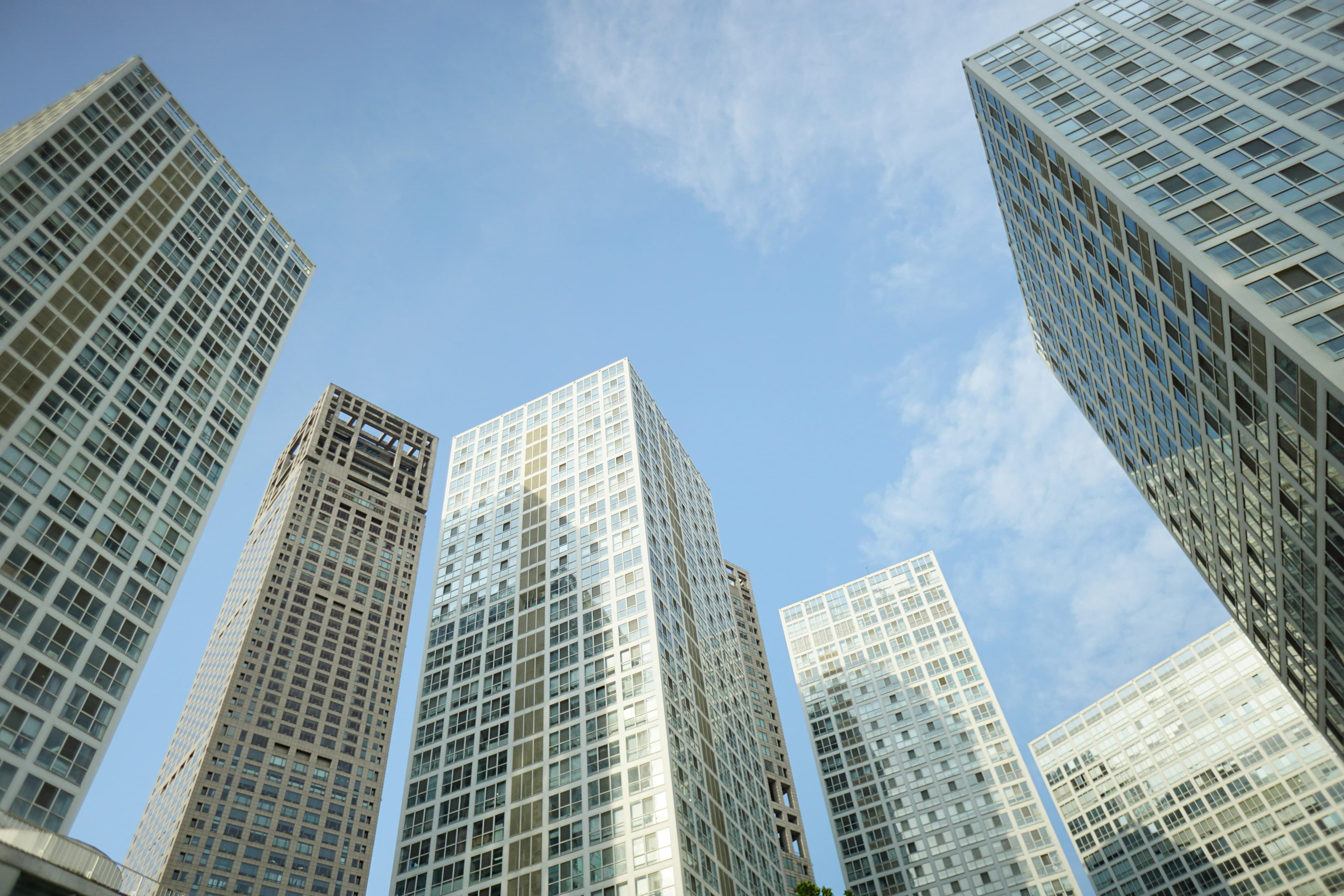 Modern skyscrapers seen from below against an open sky.